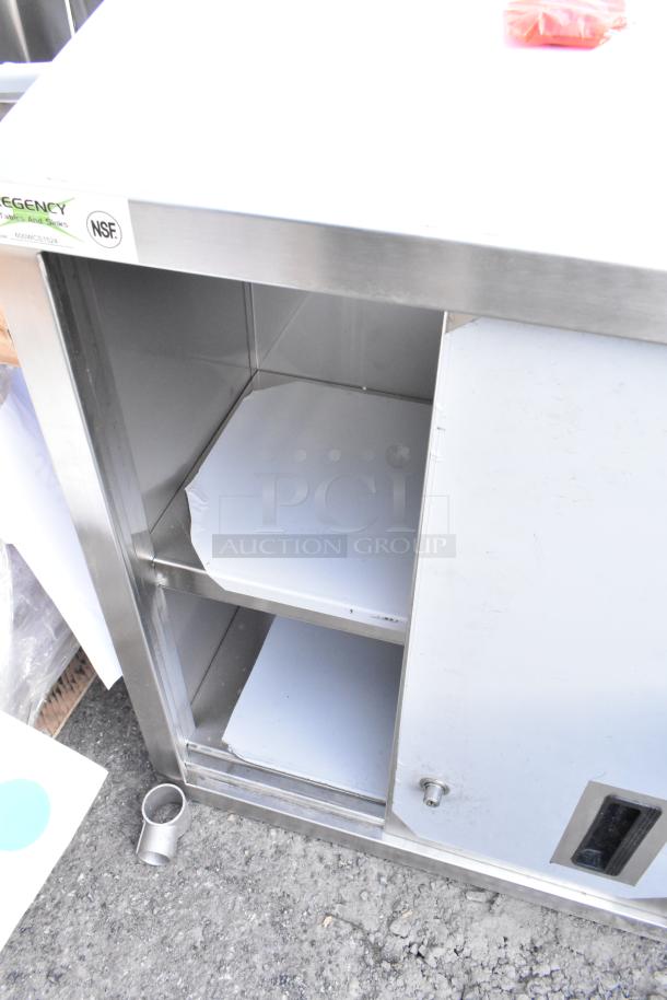 BRAND NEW Regency 600WCS1524 24" stainless steel wall cabinet with sliding doors, minor scratches visible, NSF certified.