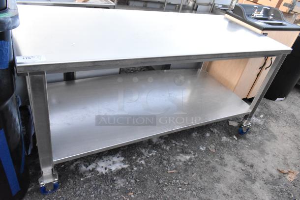 Brand new stainless steel table with under shelf and commercial casters, scratch and dent condition, auction tag visible.