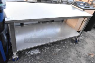 Brand new stainless steel table with under shelf and commercial casters, scratch and dent condition, auction tag visible.