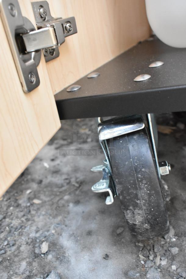 Brand new Ozark River portable hand sink, maple laminate cabinet, single basin, close-up of caster wheel.