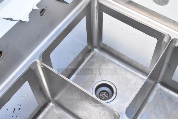 L-shaped Regency 600S3141414C stainless steel 3-bay sink with dual drain boards, no legs, scratch and dent condition.