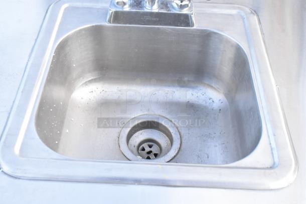 QualServ stainless steel single bay portable sink with faucet. Visible wear, mounted on commercial casters for mobility.