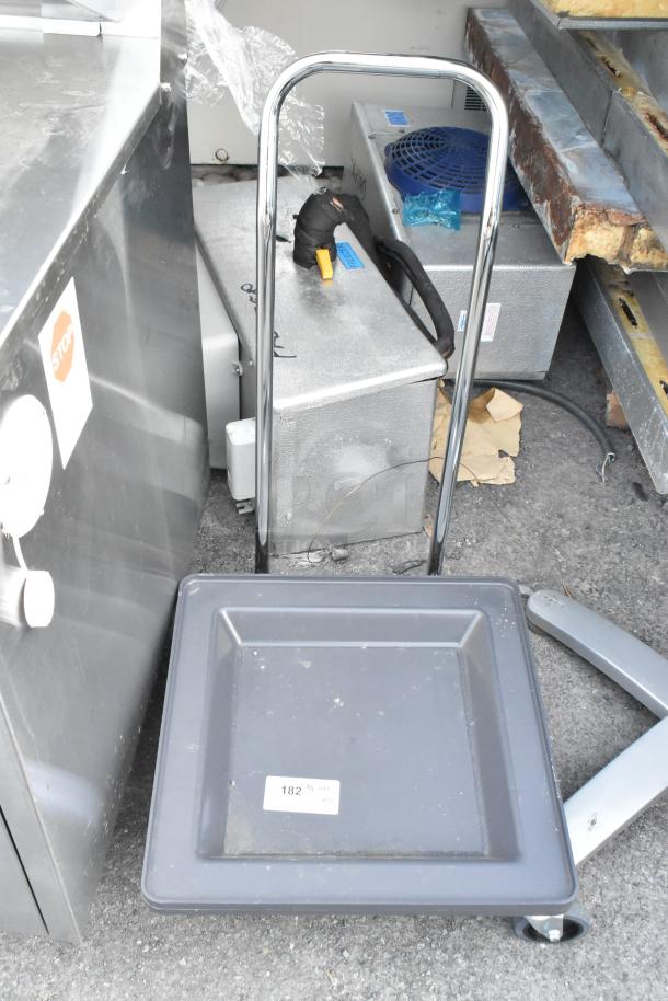 Dish caddy dolly with chrome handle and wheels. Includes a metal table base. Slight wear visible. Label reads: "182".