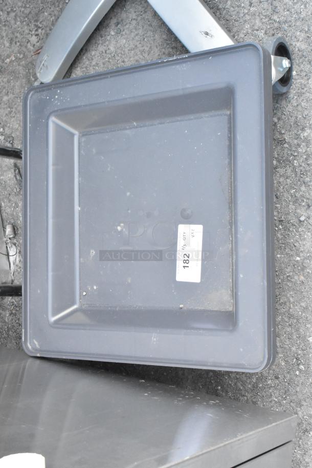 Dish caddy dolly with label and metal table base on concrete. Slight wear visible. Auction tag with number 182.