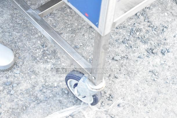 Stainless steel table with under shelf, drawer, and durable commercial casters. Slight wear visible on casters.