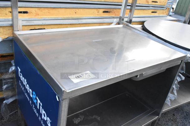Stainless steel table with under shelf and drawer, on commercial casters. Features branding and label "183 QTY 1."