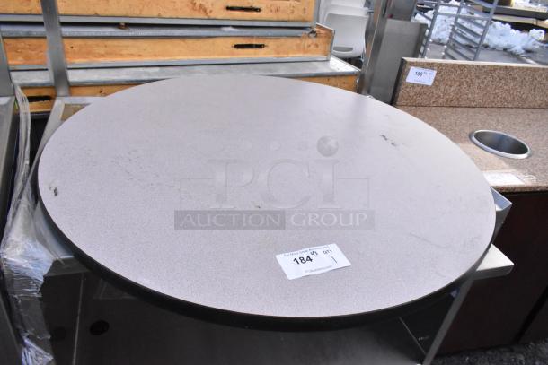 Round tabletop with light gray surface, visible marks, and black edge. Auction label "184" indicates item number.