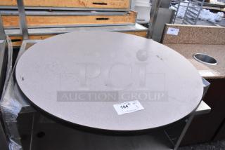 Round tabletop with light gray surface, visible marks, and black edge. Auction label "184" indicates item number.