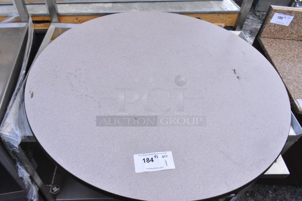 Round tabletop with light gray speckled surface, slight wear marks visible. Auction tag reads "184, QTY 4."