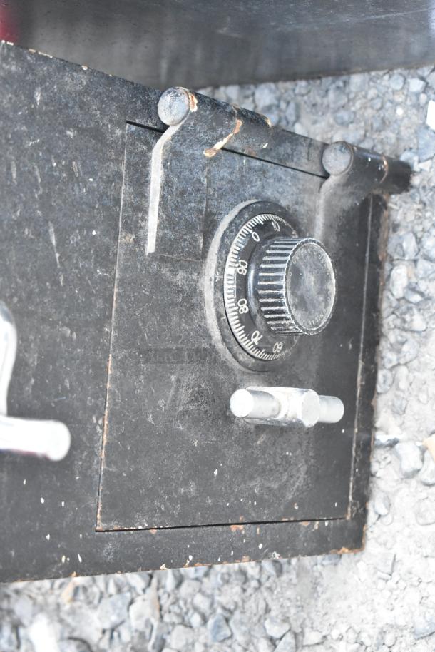 Black metal single compartment safe with dial lock, no combination included, showing signs of wear and rust.