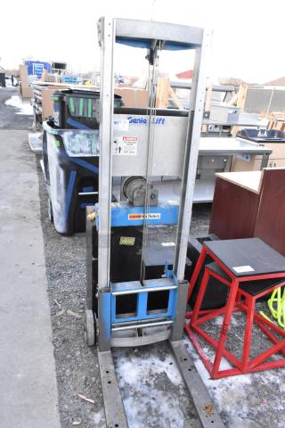 Genie Lift hand operated lift truck, steel frame, manual controls, visible safety label, outdoor condition.