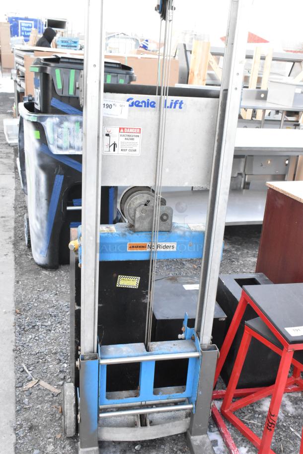 Genie Lift hand operated lift truck, blue and silver, visible safety labels, good condition.