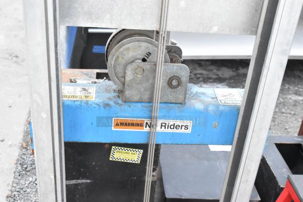 Genie Lift Hand Operated Lift Truck with visible steel cable and "No Riders" warning label; used condition.