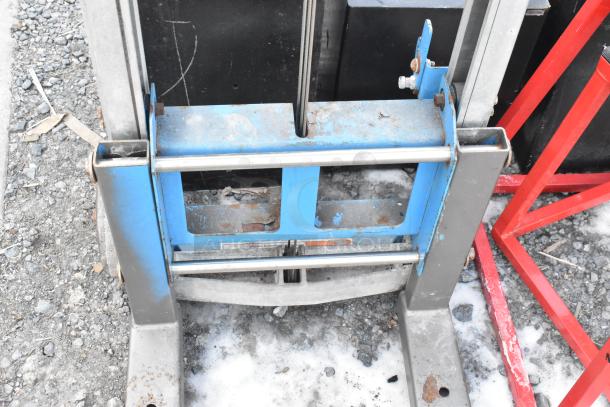 Genie Lift Hand Operated Lift Truck, metal frame, signs of rust, used condition, blue and gray, visible wear.