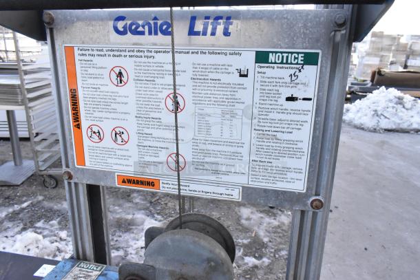 Genie Lift hand operated lift truck with safety and operating instructions label shown. Durable metal frame, in used condition.