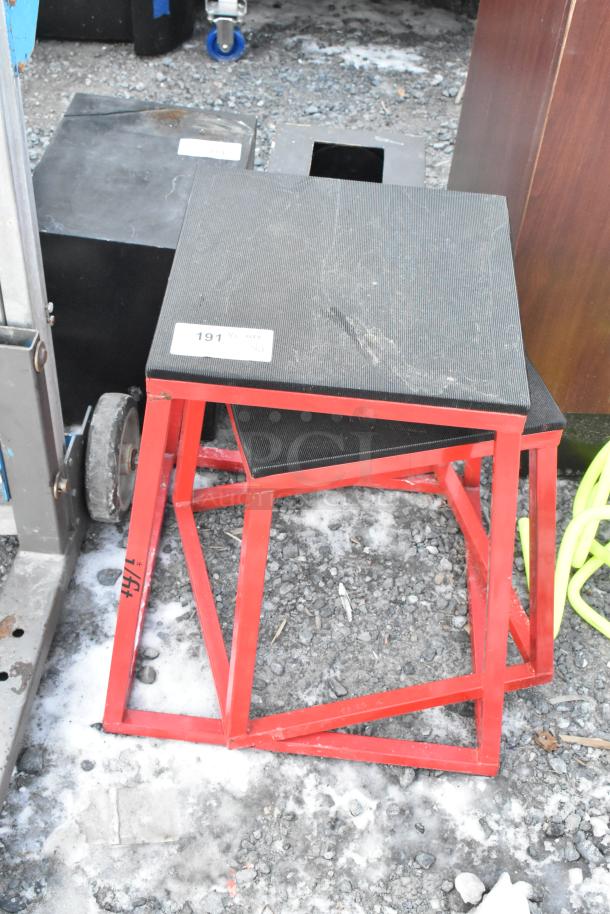 Two black and red stools with metal frames and textured surfaces, showing minor wear. Tag reads "191" for auction reference.