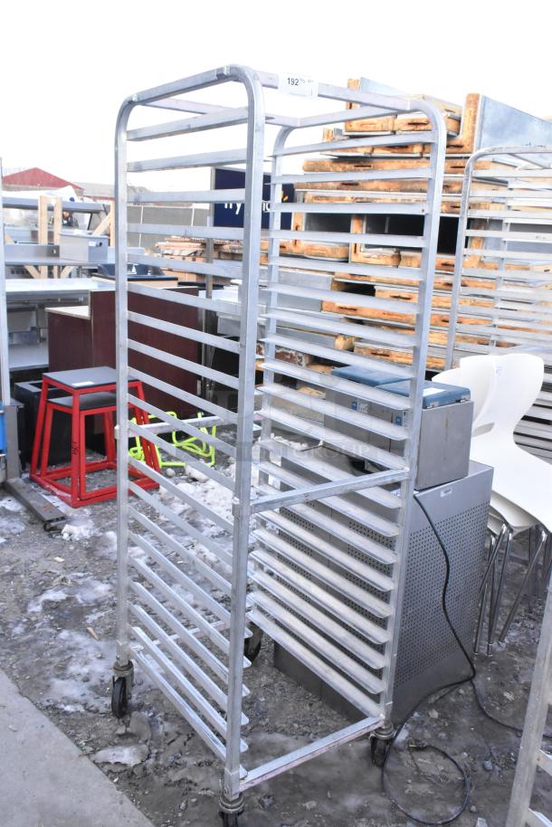 Commercial pan transport rack with multiple shelves, sturdy metal frame, on commercial casters, in used condition.