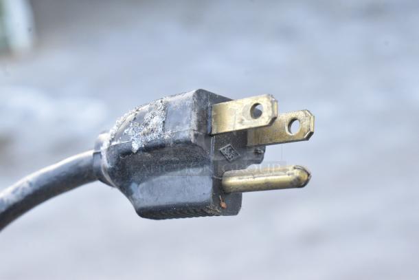Close-up of a three-pronged power plug with signs of wear. Plug suitable for Karma 104 Chocolate Warmer, 120V, 1 Phase.