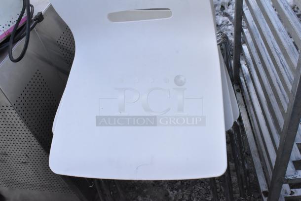 6 white poly chairs with chrome finish legs, modern design. Minor wear visible. Stackable for easy storage.