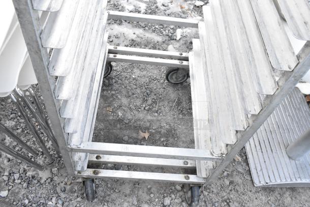 Commercial pan transport rack on sturdy casters, aluminum build, multiple shelves, used condition, suitable for bakeries.
