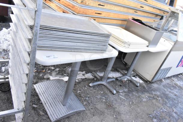 Three white dining height tables with metal baking pans and white poly lids stacked on top; includes auction tag.
