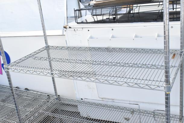 Chrome finish 4-tier wire shelving unit in good condition, buyer must dismantle; freight charges apply.