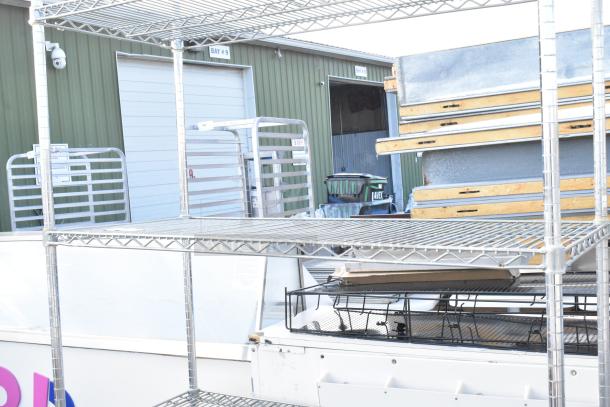 Chrome finish 4-tier wire shelving unit outdoors, sturdy construction. Buyer must dismantle. Freight charges apply.