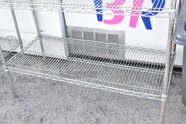 Chrome finish 4 tier wire shelving unit with visible rust on legs. Buyer must dismantle for shipping.