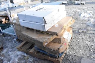 Stack of boxes on a pallet with visible scratch and dent labels, including brands like Kohler, in new condition.