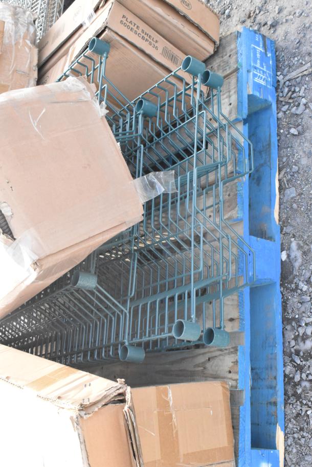 Stack of boxed items on a pallet, including green metal frames and cartons marked "Plate Shelf 600ESCPS36." Scratch and dent condition.