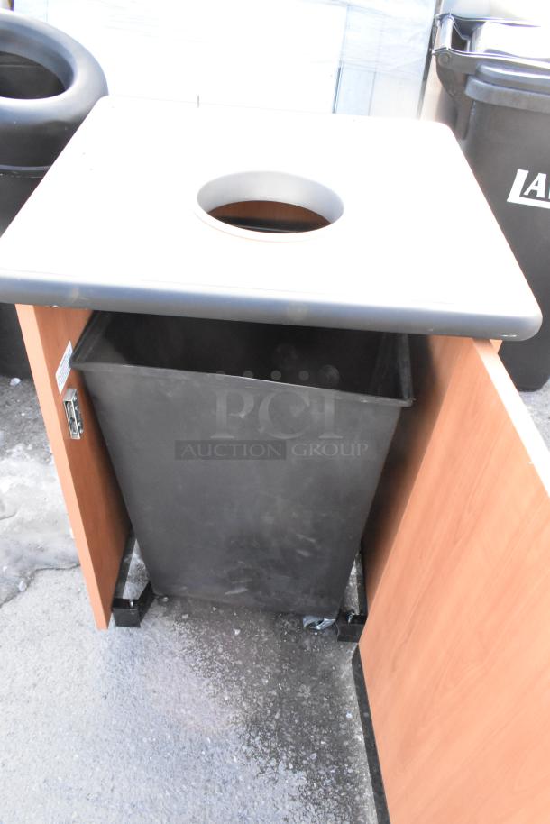 Wooden trash can shell with a lid and two black trash cans. Features durability and modern design. Ideal for commercial settings.