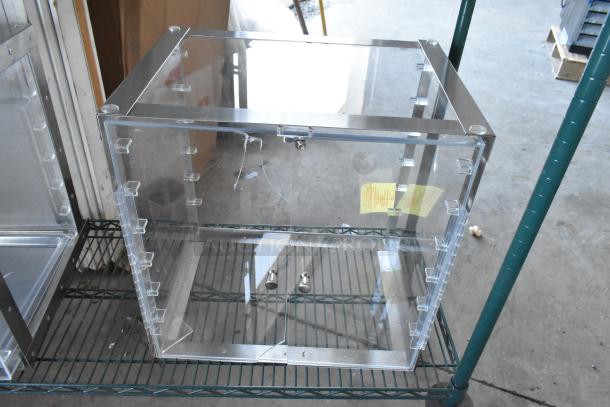 Clear poly countertop cabinet with metal frame, showing minor scratches. Includes lock and key. Measures approximately 2 feet. Brand new.