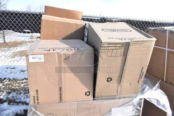 Stack of boxes labeled "Scratch and Dent" containing new items like napkins, towels, containers, mixing glasses.