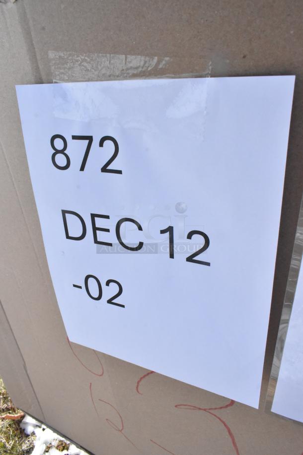 Cardboard box with a paper label reading "872 DEC 12 -02." Contains 16 new scratch and dent items, including a bakery dolly and foam cups.