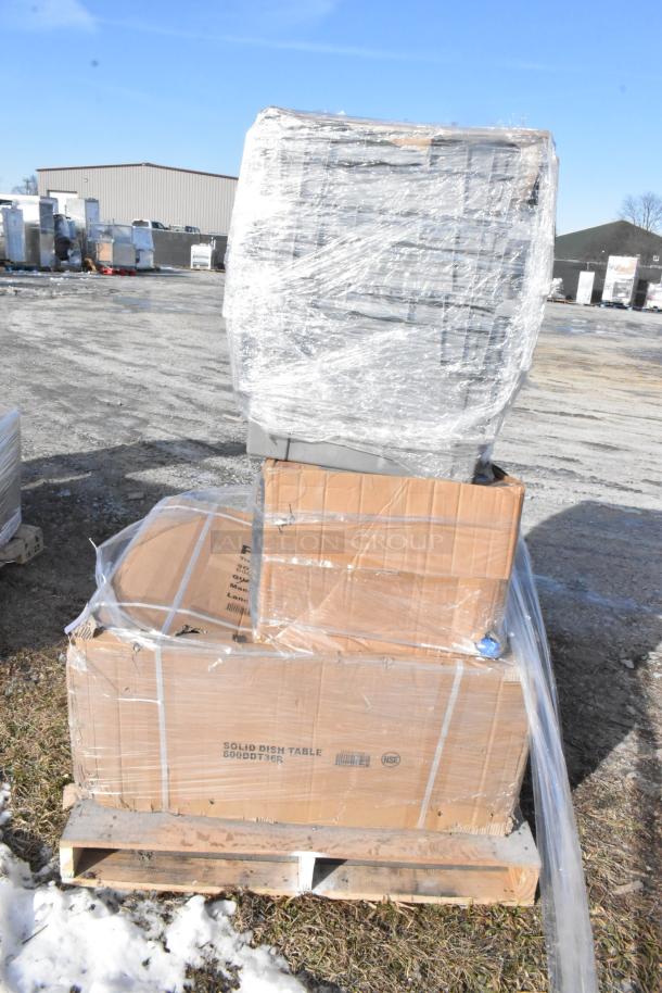 Stacked boxes wrapped in plastic on a pallet, including items like Regency 600DDT36R dish table, shown in outdoor setting.