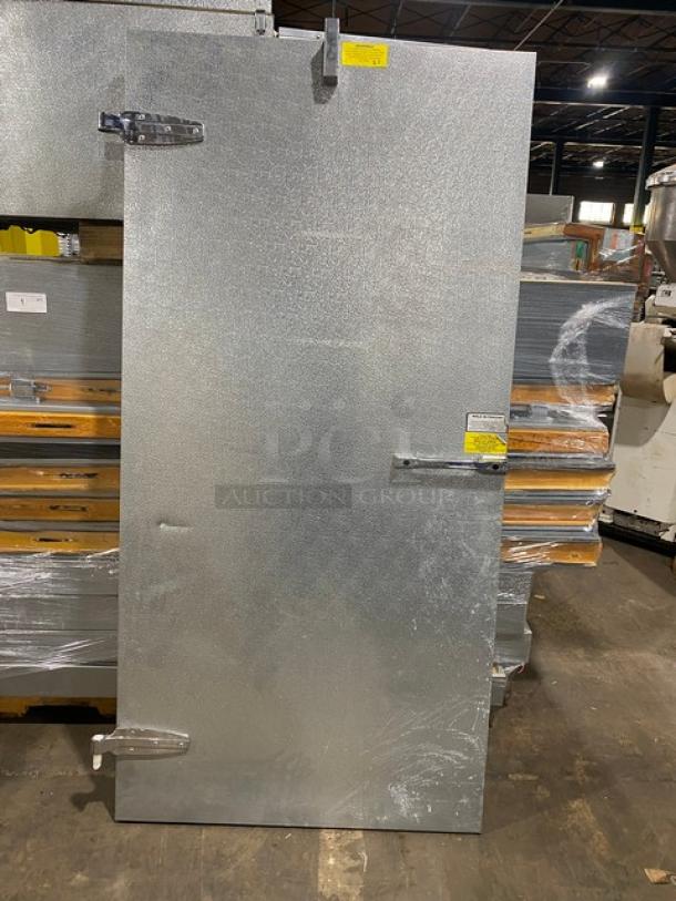 Galvanized steel industrial door with locking hinges, in new condition, features safety labels and hardware, suitable for commercial use.