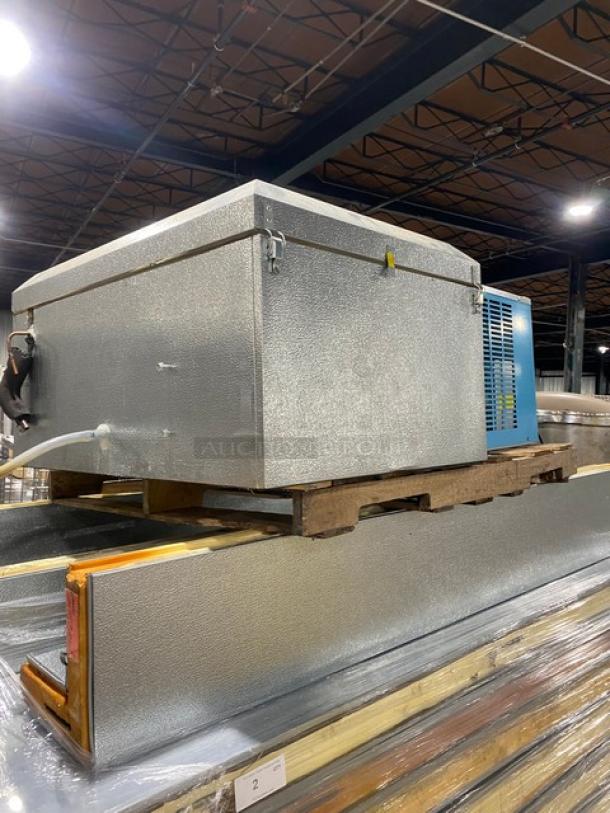 Large industrial refrigeration unit on pallet, gray metal exterior, mounted on wooden base, well-maintained.