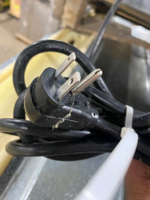 Black electrical power cord with visible surface wear and scuff marks, secured with a white zip tie.