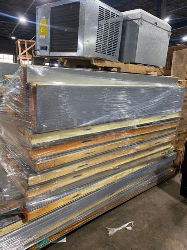 Stack of commercial refrigerator doors and units, wrapped in plastic. Used condition, visible scuffs and marks.