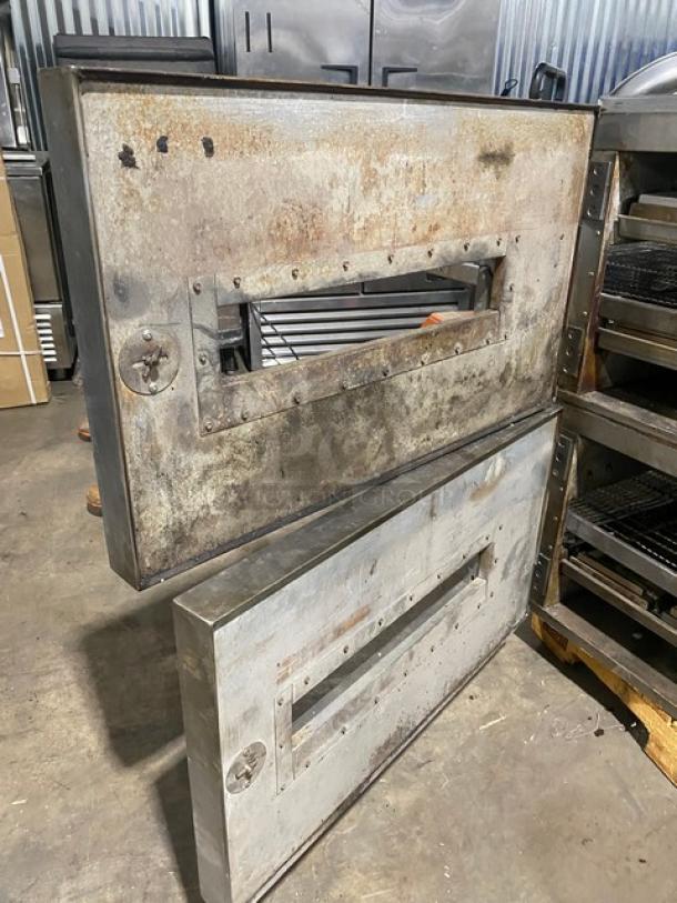 Industrial metal oven doors, used condition, with visible rust and wear. Hinges and locking mechanism intact.