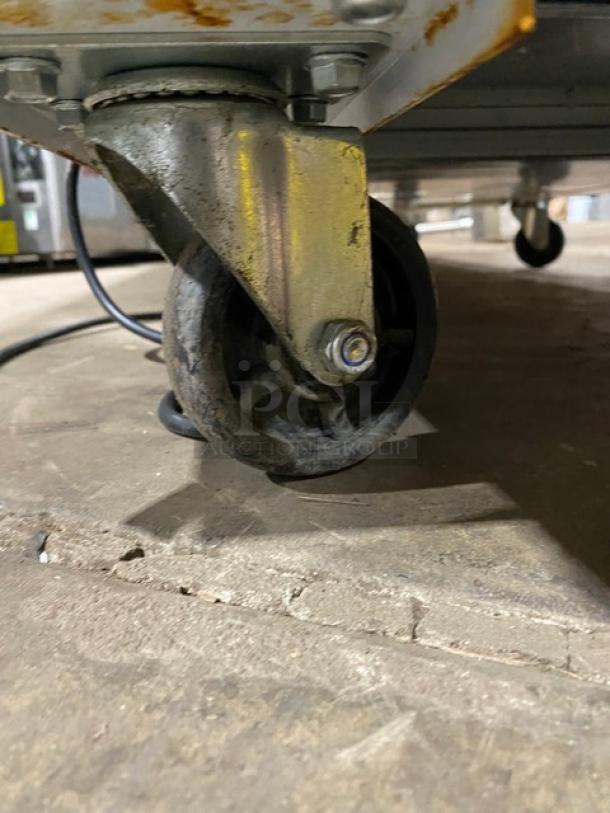 Swivel caster wheel attached to metal furniture, showing signs of rust and wear. Suitable for heavy-duty use.