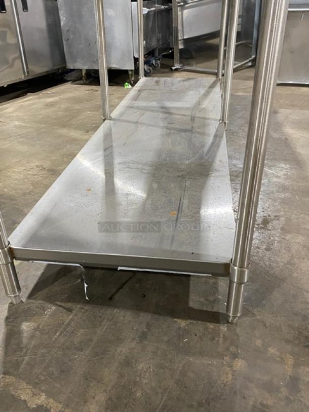 Stainless steel commercial kitchen shelf in used condition, sturdy metal frame, some surface wear, ideal for storage.
