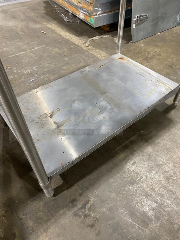 Stainless steel utility cart shelf with visible wear and rust, used condition, sturdy structure, industrial setting.