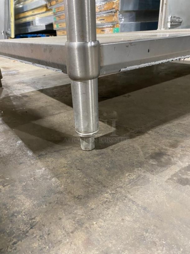 Stainless steel table leg with adjustable foot on concrete floor; appears sturdy with brushed finish and no visible damage.
