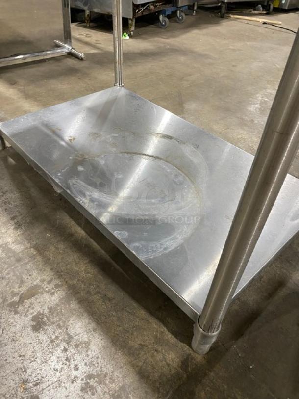 Stainless steel utility shelf on wheels, showing signs of wear with visible scuffs and scratches, sturdy construction.