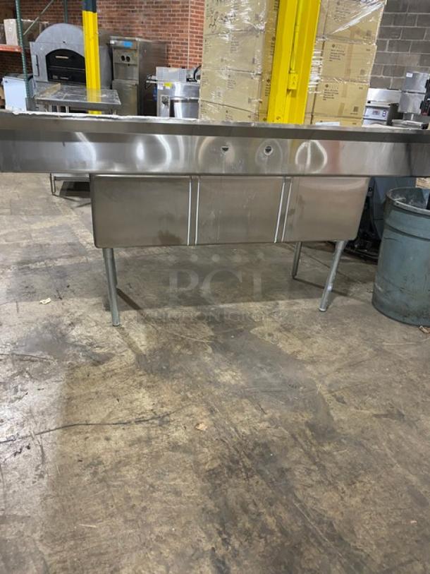 Stainless steel commercial sink with two compartments, pre-drilled faucet holes. Scratches and signs of use visible.