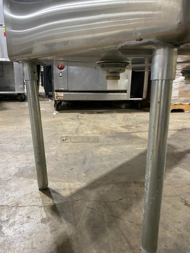 Stainless steel commercial sink with sturdy metal legs, slightly worn condition, suitable for industrial kitchen use.