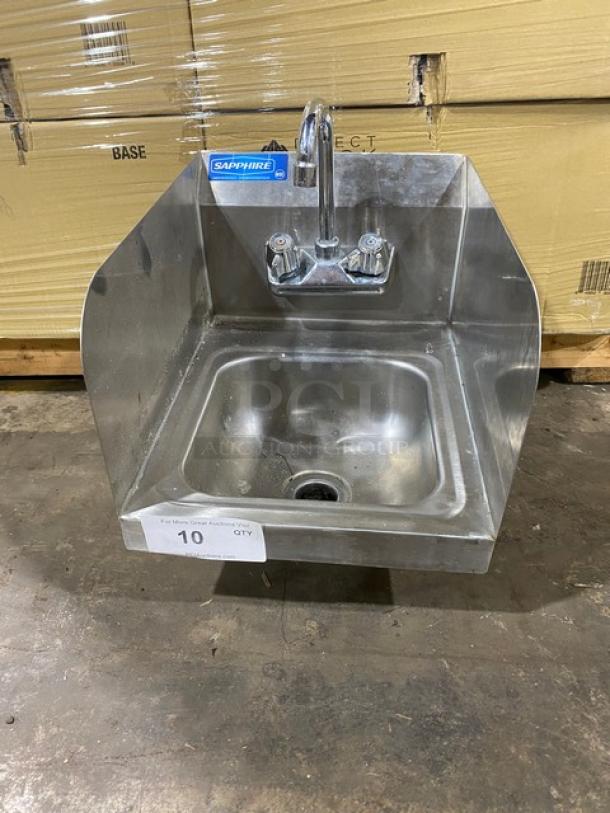Stainless steel wall-mounted sink with dual handles and "Sapphire" label, in used condition with minor surface wear.