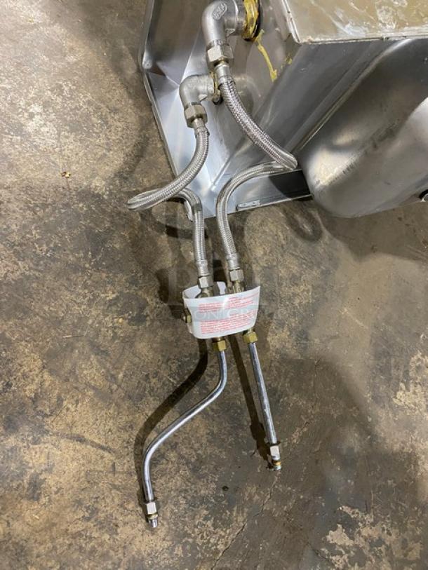 Stainless steel hydraulic hoses and fittings with attached label on a metal surface; item appears in good condition.