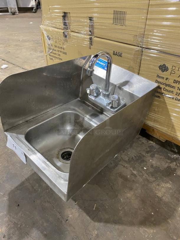 Stainless steel hand sink with side splashes and faucet, in good condition. Includes wall-mounting hardware and drain.